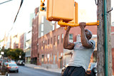 Young black man doing chin ups from crossing light in street