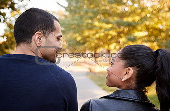 Young Hispanic couple walking in Brooklyn park, back view