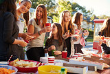 Girls stand talking at a block party food table, close up