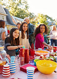 Pre-teen girls smiling to camera at a block party food table