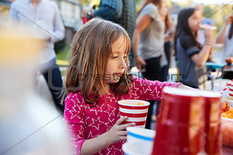 Four year old girl helping herself to food at a block party