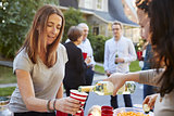 Neighbour pouring a woman a cup of wine at a block party