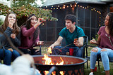 Teenage friends eating sÕmores around a firepit