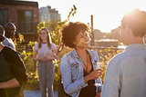 Friends talking at a rooftop party backlit by sunlight