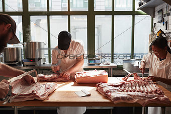 Three butchers preparing pork at a butcher's shop