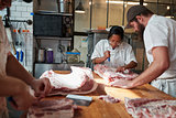 Three butchers preparing meat,cuts of meat to sell at a butcher's shop