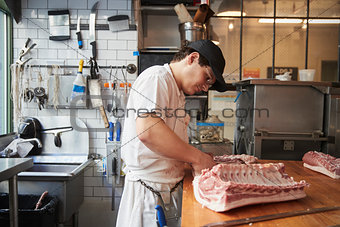 Young butcher cutting meat to sell at a butcher's shop