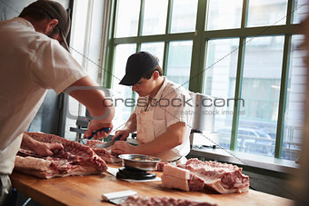Two butchers cutting meat to sell at a butcher's shop