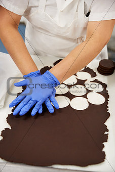 Young woman cutting out cookie dough circles at a bakery