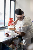 Young black woman frosting a cake at a bakery