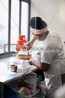 Young black woman frosting a cake at a bakery