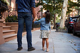 Father and daughter taking a walk down the street, back view