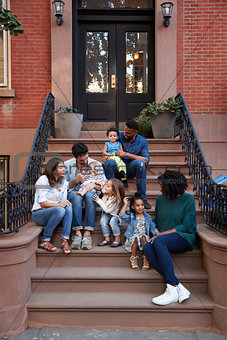 Two families with kids sitting on front stoops, vertical