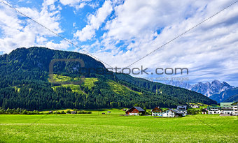 Village among green meadows and Austrian Alps