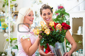 Two women looking at bouquet of roses in flower shop