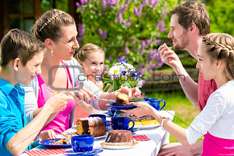Family having coffee time in garden eating cake