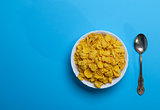 cornflakes in a white ceramic plate and an iron spoon 