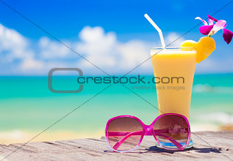picture of fresh banana and pineapple juice and sunglasses on tropical beach