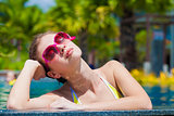 Beautiful young woman in sunglasses relaxing in luxury pool