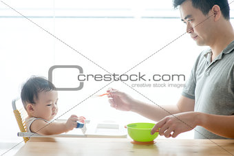 Father feeding baby solid food.