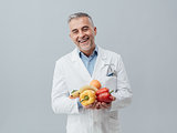 Smiling nutritionist holding fresh vegetables and fruit