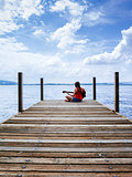 Woman playing acoustic guitar by the lake