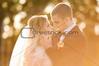 groom is touching bride gently in a sun light