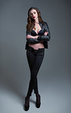 Studio fashion shot: portrait of attractive young woman in pants, bra and leather jacket. Full length 