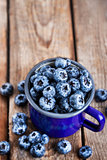 Fresh ripe blueberries and in blue enamel mug