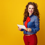 smiling trendy woman on yellow background with tablet PC