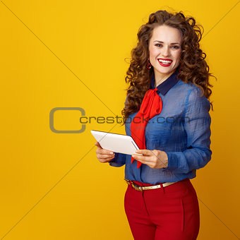 smiling trendy woman on yellow background with tablet PC