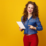 smiling modern woman on yellow background using tablet PC