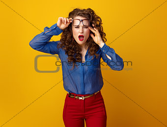 stylish woman in glasses on yellow background squinting