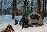 tent on the snow in the winter forest and bonfire