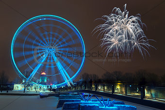 Fireworks explode near the observation wheel at night.