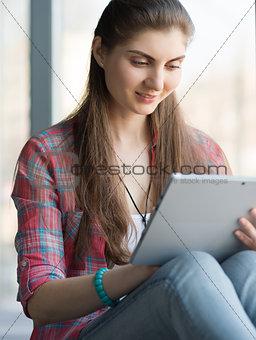 Portrait of Attractive Woman Working on Tablet near Big Window.
