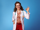 smiling pediatrist woman showing ok gesture on blue