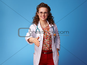 smiling paediatrician doctor giving hand for handshake on blue