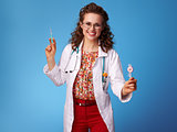 smiling pediatrist doctor with syringe and lollypop on blue