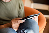 young man using a tablet sitting in a couch