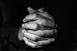 man with his hands clasped, in black and white