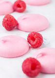 Pink sweet meringue shells with fresh raspberries