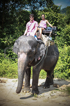 Young couple tourists rides on elephants in elephant farm in Thailand. Attractions for tourists.