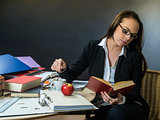 Beautiful teacher sitting at her desk reading