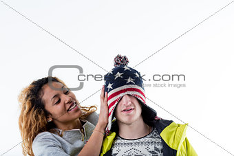 Young cheerful woman putting cap on man head
