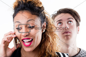 Tired man standing behind woman talking on phone