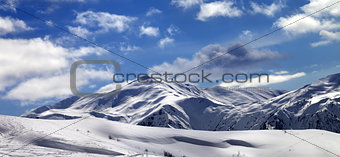 Panoramic view on ski slope and beautiful sky with clouds in sun