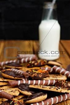 Milk with a cookie in a glass bottle on a wooden background