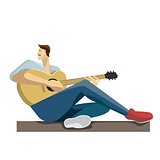 Caucasian musician sitting with the guitar in hands. Hipster man playing the acoustic guitar.