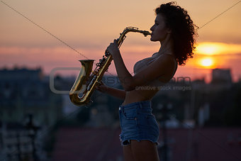 Young girl with a saxophone on the roof